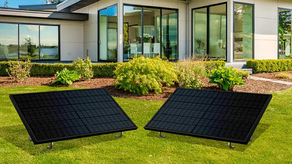 Zwei aufgeständerte Solarmodule auf einer Rasenfläche vor einem Haus